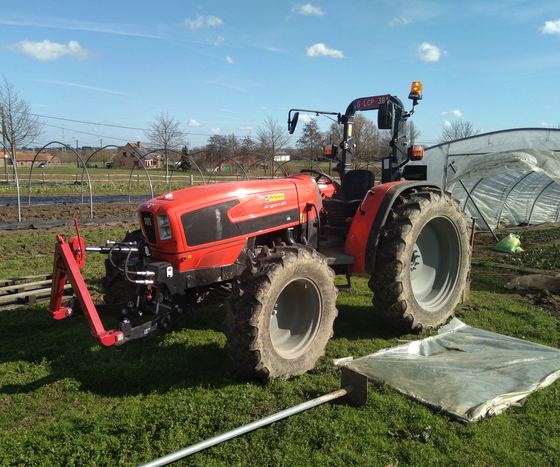 De tractor naast de serres in het vroege voorjaar.